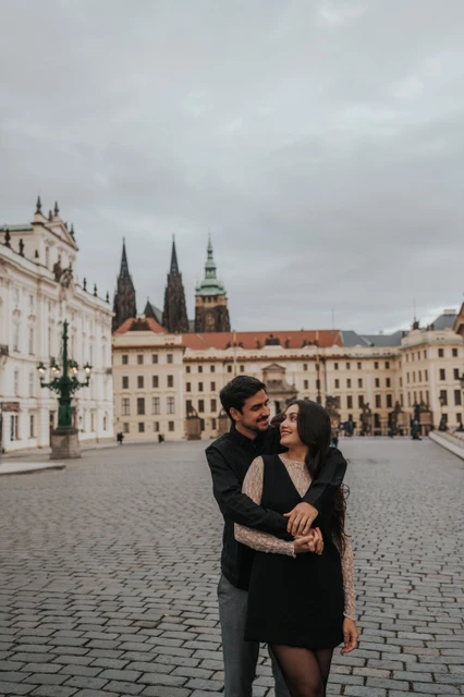 Couple sharing a close embrace in the square with cathedral spires behind them during their engagement photoshoot in Prague.