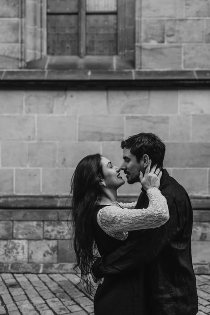 Prague engagement photoshoot with a close kiss in black and white Black-and-white close portrait of the couple kissing beside the cathedral wall during their Prague engagement photoshoot.