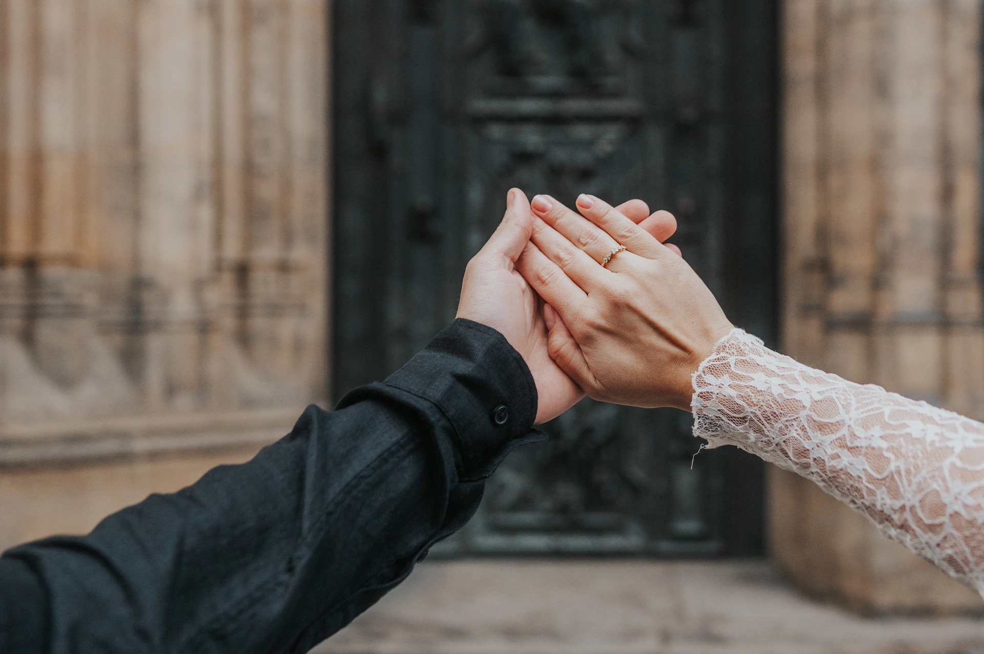 Prague engagement photoshoot with a close-up of the ring Close-up of the engagement ring on the woman's hand resting against her partner's palm during their Prague engagement photoshoot.
