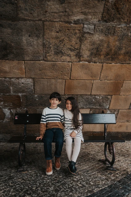 Prague family photoshoot: the twins together beneath Charles Bridge The twins sitting close together on a bench beneath Charles Bridge during their Prague family photoshoot.