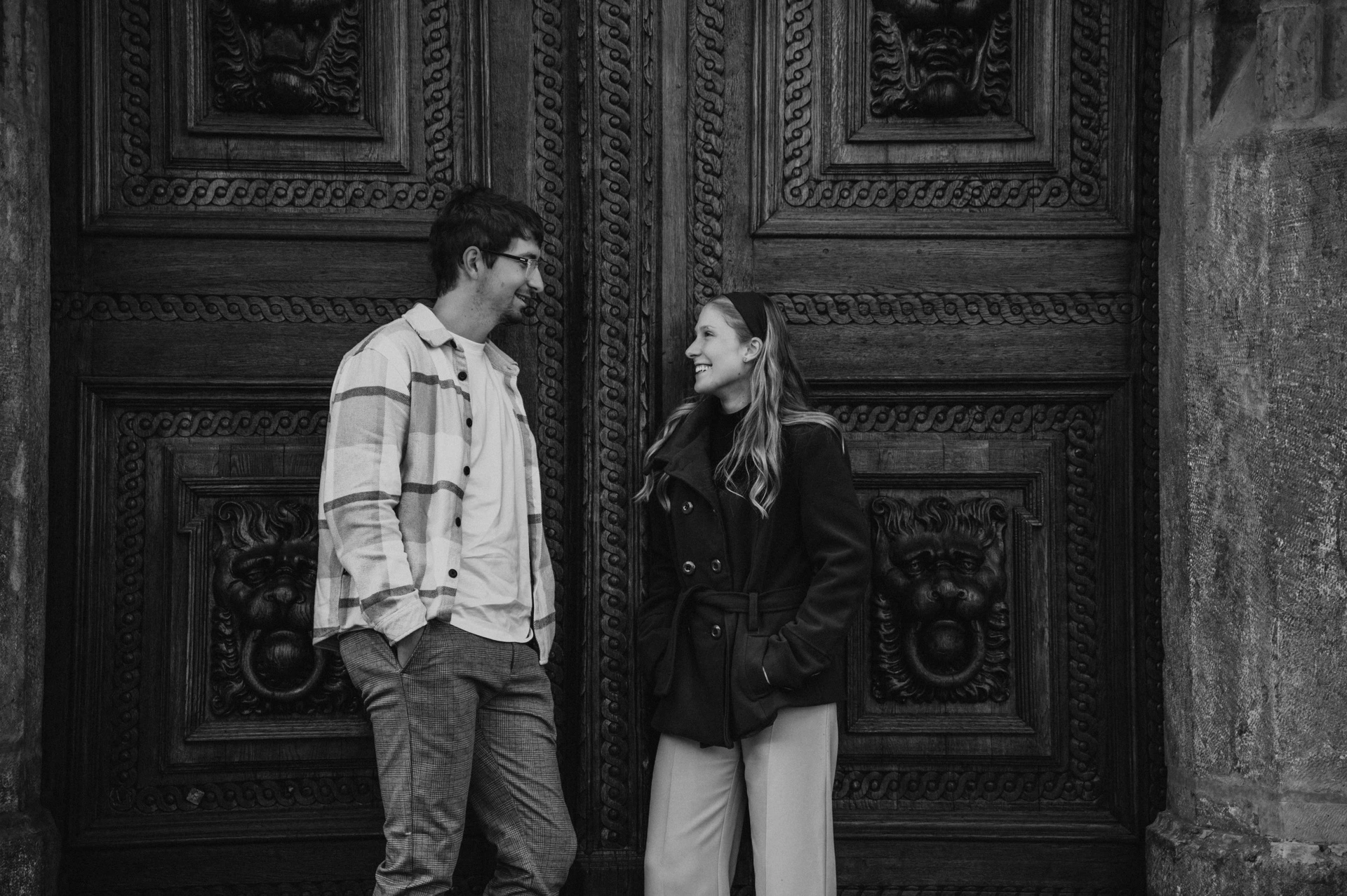 Black and white portrait at the carved wooden doors during a couple photoshoot in Prague.