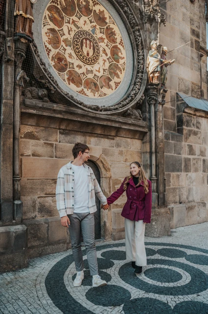 Couple holding hands on the patterned pavement by the clock during a couple photoshoot in Prague.