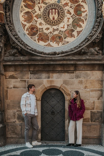 Prague couple photoshoot: couple standing beneath the Astronomical Clock. Couple standing beneath the Astronomical Clock during a couple photoshoot in Prague.