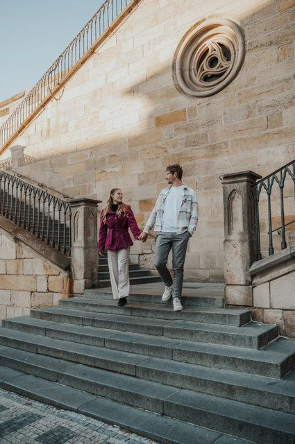 Prague couple photoshoot: couple walking down the stairs beside Charles Bridge. Couple walking down the stairs beside Charles Bridge during a couple photoshoot in Prague.