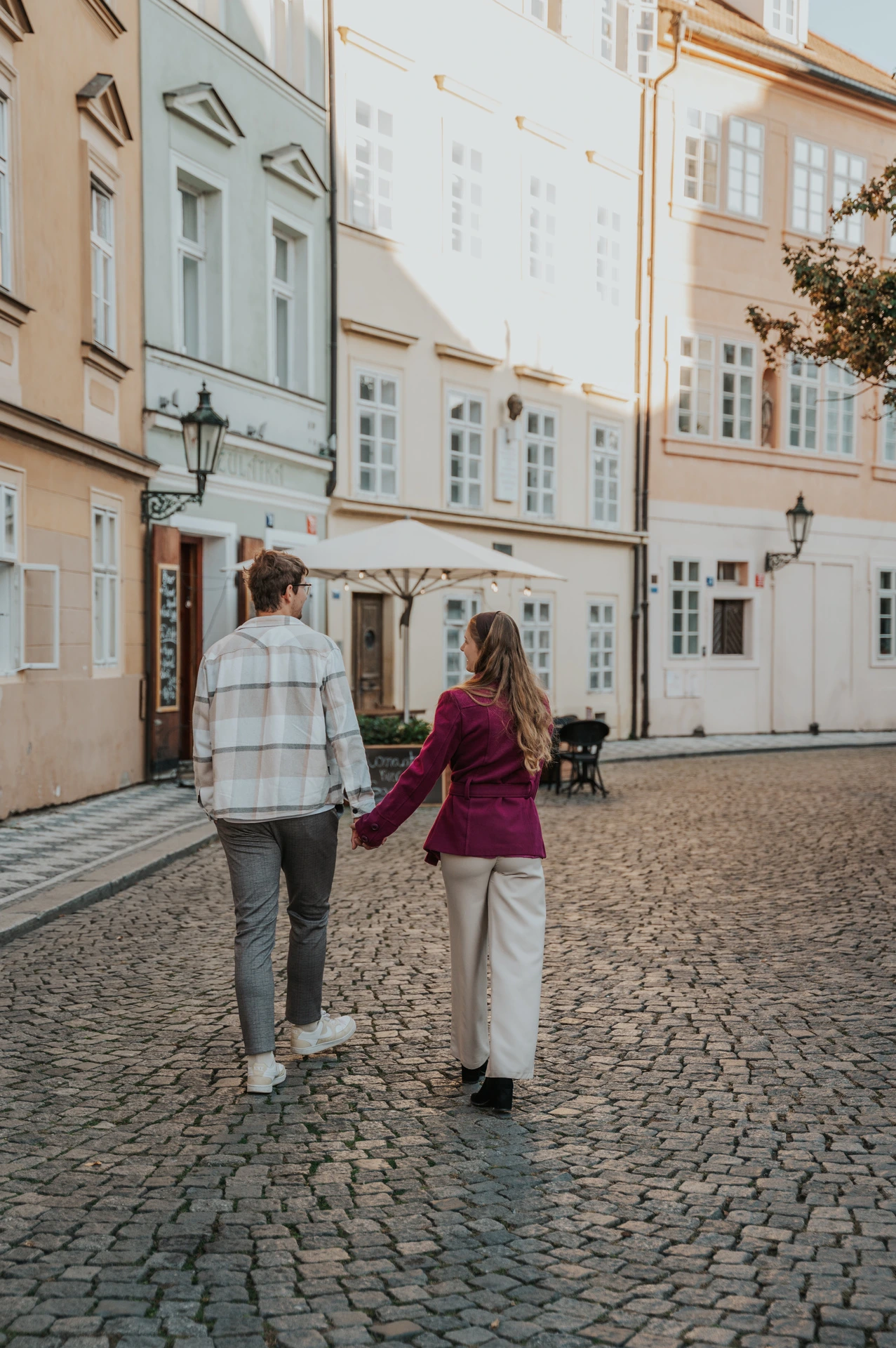 Couple walking hand in hand along a cobbled Kampa street during a couple photoshoot in Prague.