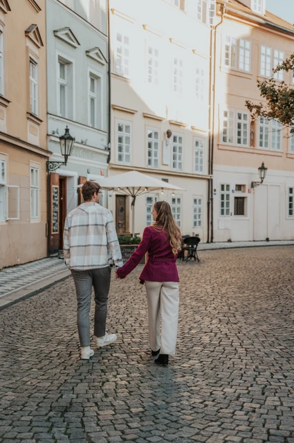 Prague couple photoshoot: couple walking hand in hand along a cobbled Kampa street. Couple walking hand in hand along a cobbled Kampa street during a couple photoshoot in Prague.
