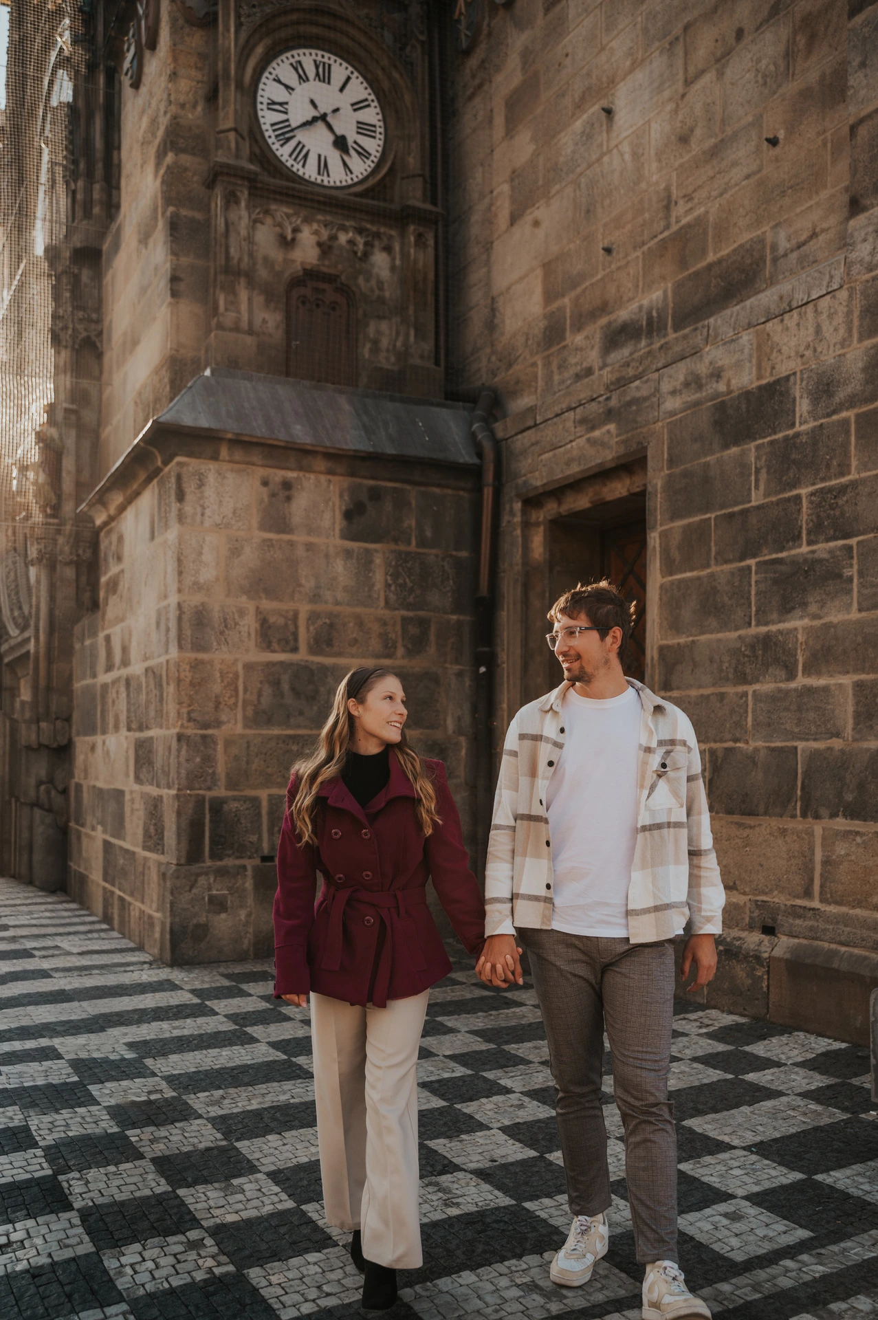 Couple walking hand in hand beneath the clock during a couple photoshoot in Prague.