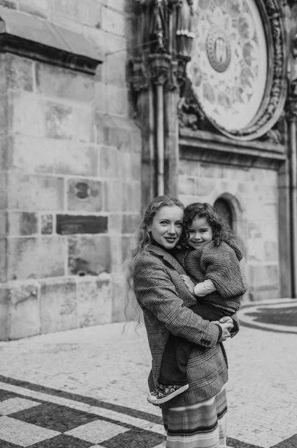 Prague family photoshoot: black and white embrace beneath the Astronomical Clock. Black and white embrace beneath the Astronomical Clock during a mother and daughter family photoshoot in Prague.