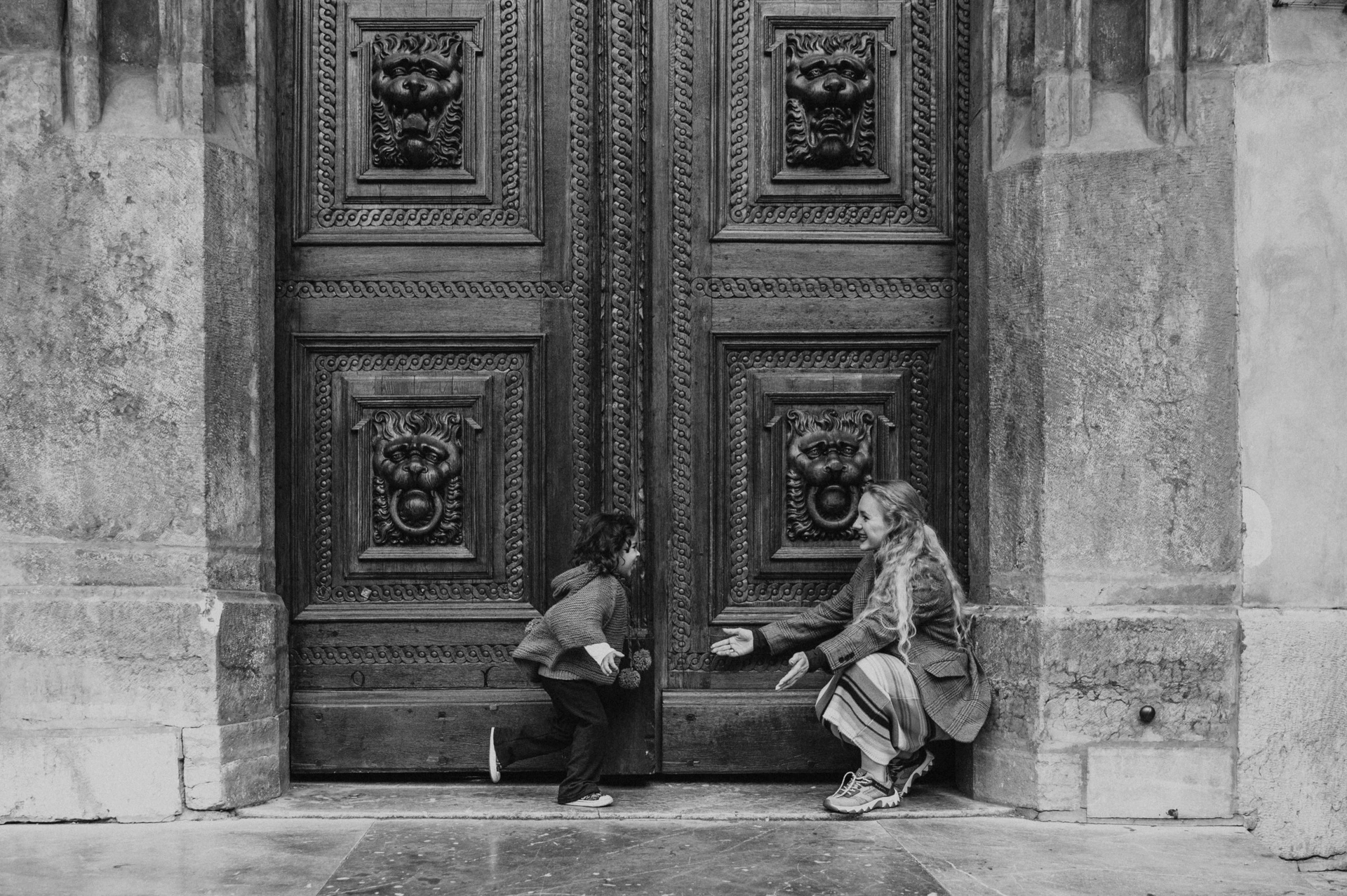 Black and white portrait of mother and daughter beside the wooden doors during a mother and daughter family photoshoot in Prague.