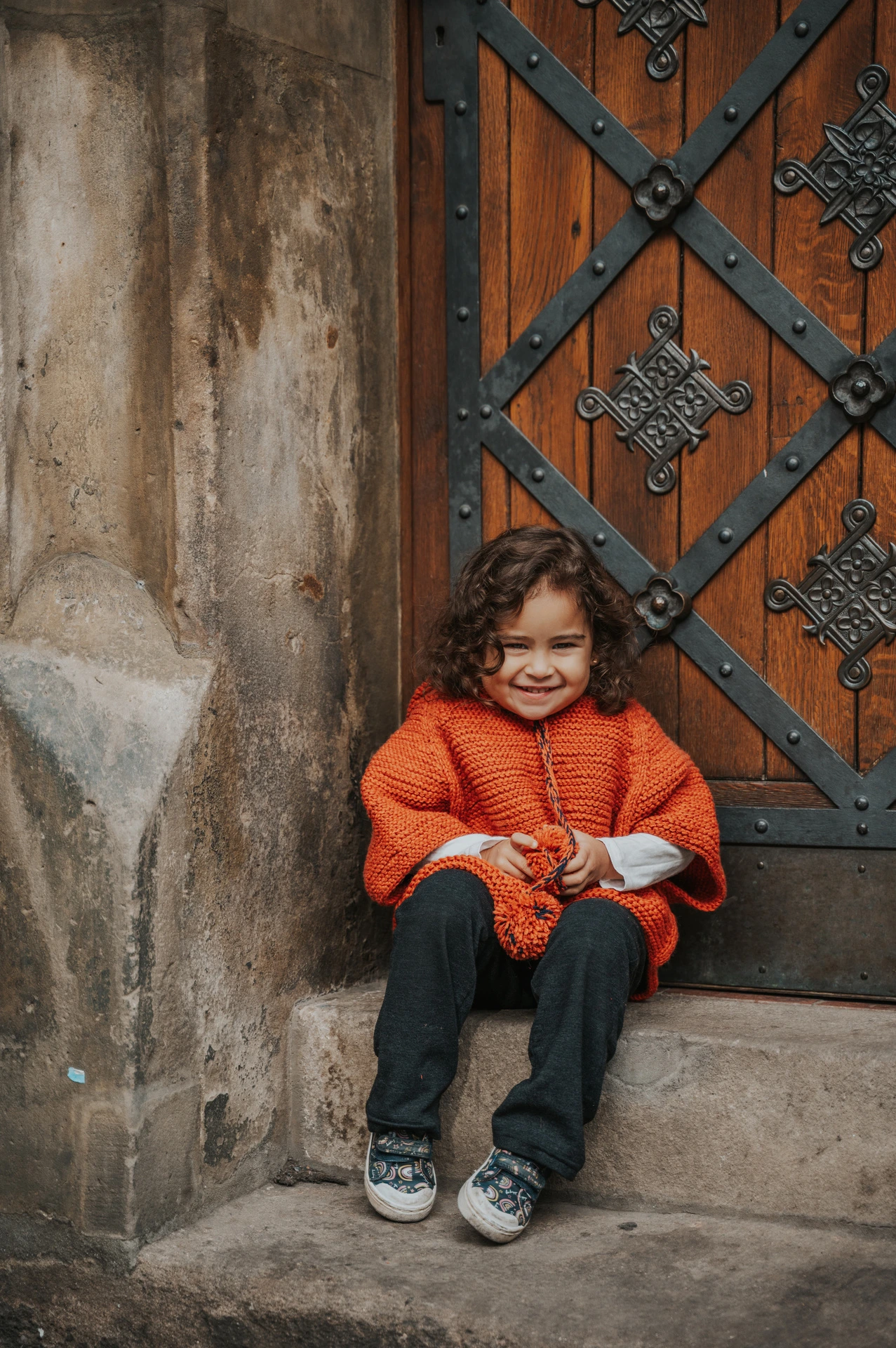 Little girl sitting in a patterned Old Town doorway during a mother and daughter family photoshoot in Prague.