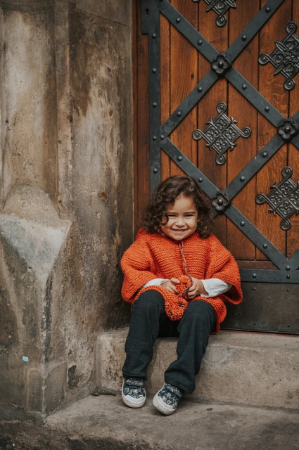 Prague family photoshoot: little girl sitting in a patterned Old Town doorway. Little girl sitting in a patterned Old Town doorway during a mother and daughter family photoshoot in Prague.