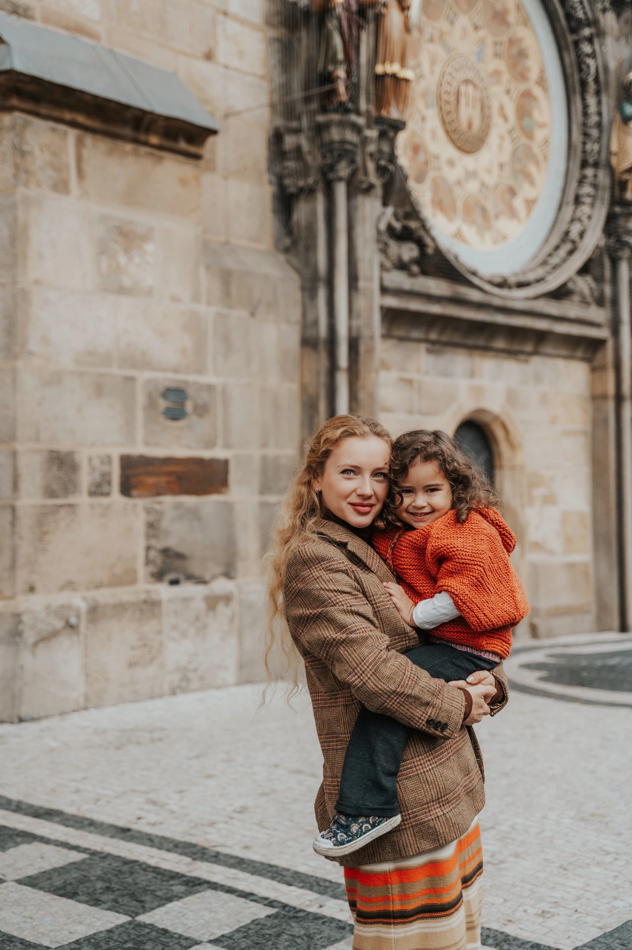 Mother and daughter cuddling by the Astronomical Clock during a mother and daughter family photoshoot in Prague.