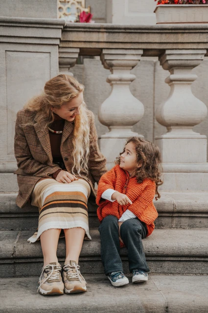 Mother and daughter exchanging smiles while sitting on the steps during a mother and daughter family photoshoot in Prague.