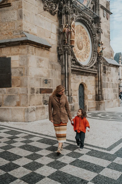 Prague family photoshoot: mother and daughter sharing a smile beneath the clock. Mother and daughter sharing a smile beneath the clock during a mother and daughter family photoshoot in Prague.