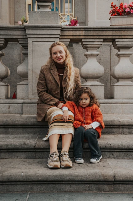 Prague family photoshoot: mother and daughter sitting together on stone steps. Mother and daughter sitting together on stone steps during a mother and daughter family photoshoot in Prague.