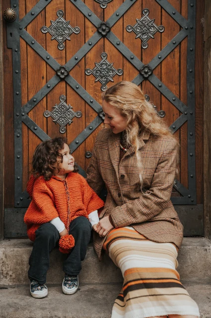Mother and daughter smiling at each other on the doorstep during a mother and daughter family photoshoot in Prague.