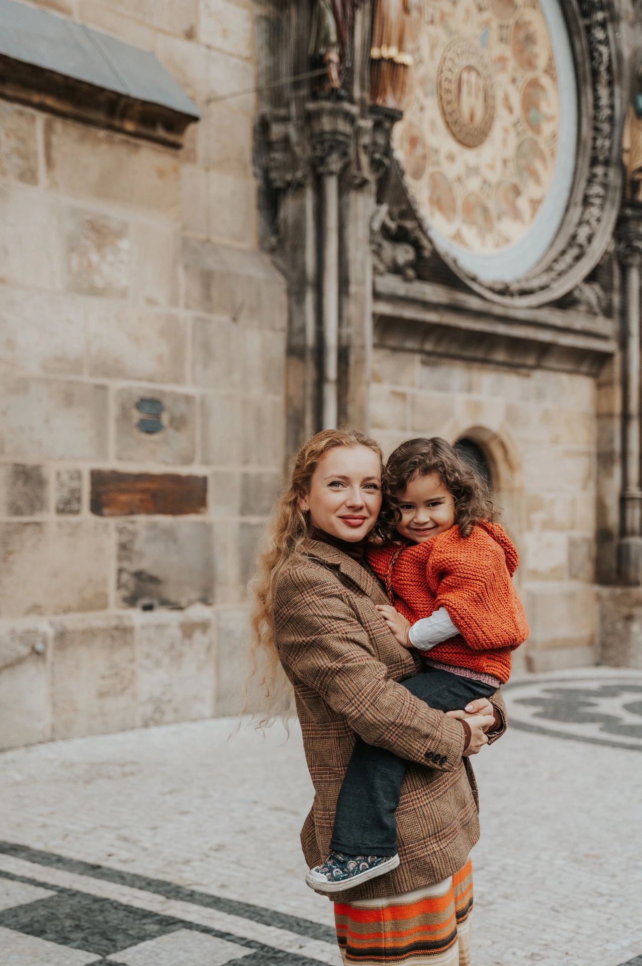 Mother holding her daughter beneath the Astronomical Clock during a mother and daughter family photoshoot in Prague.