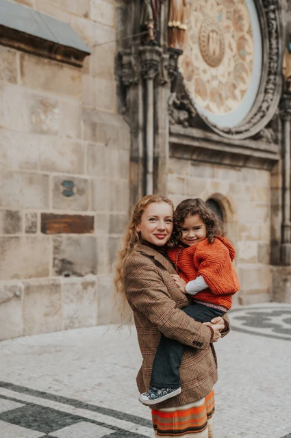 Mother holding her daughter beneath the Astronomical Clock during a mother and daughter family photoshoot in Prague.