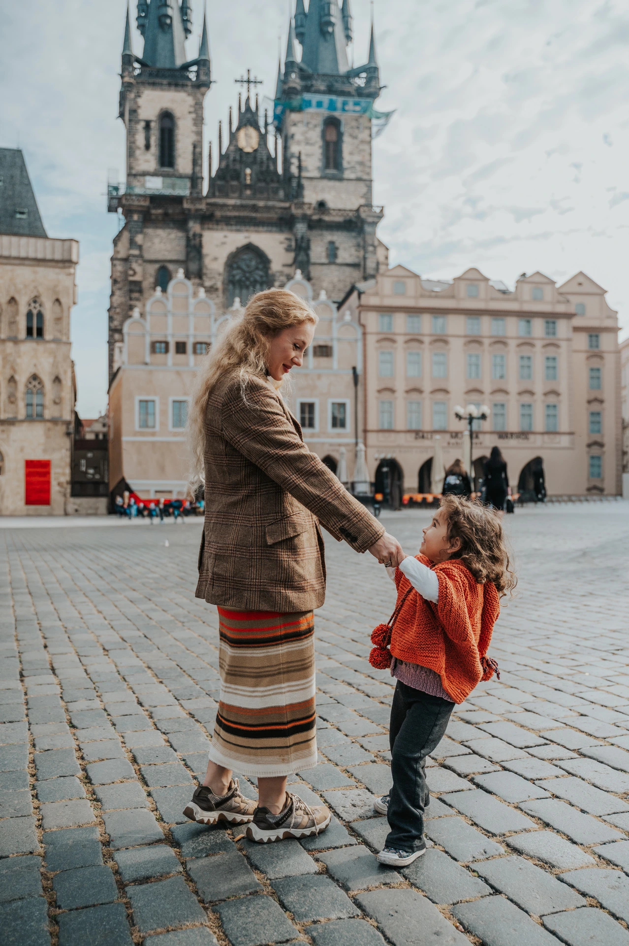 Mother holding her daughter’s hands in Old Town Square during a mother and daughter family photoshoot in Prague.