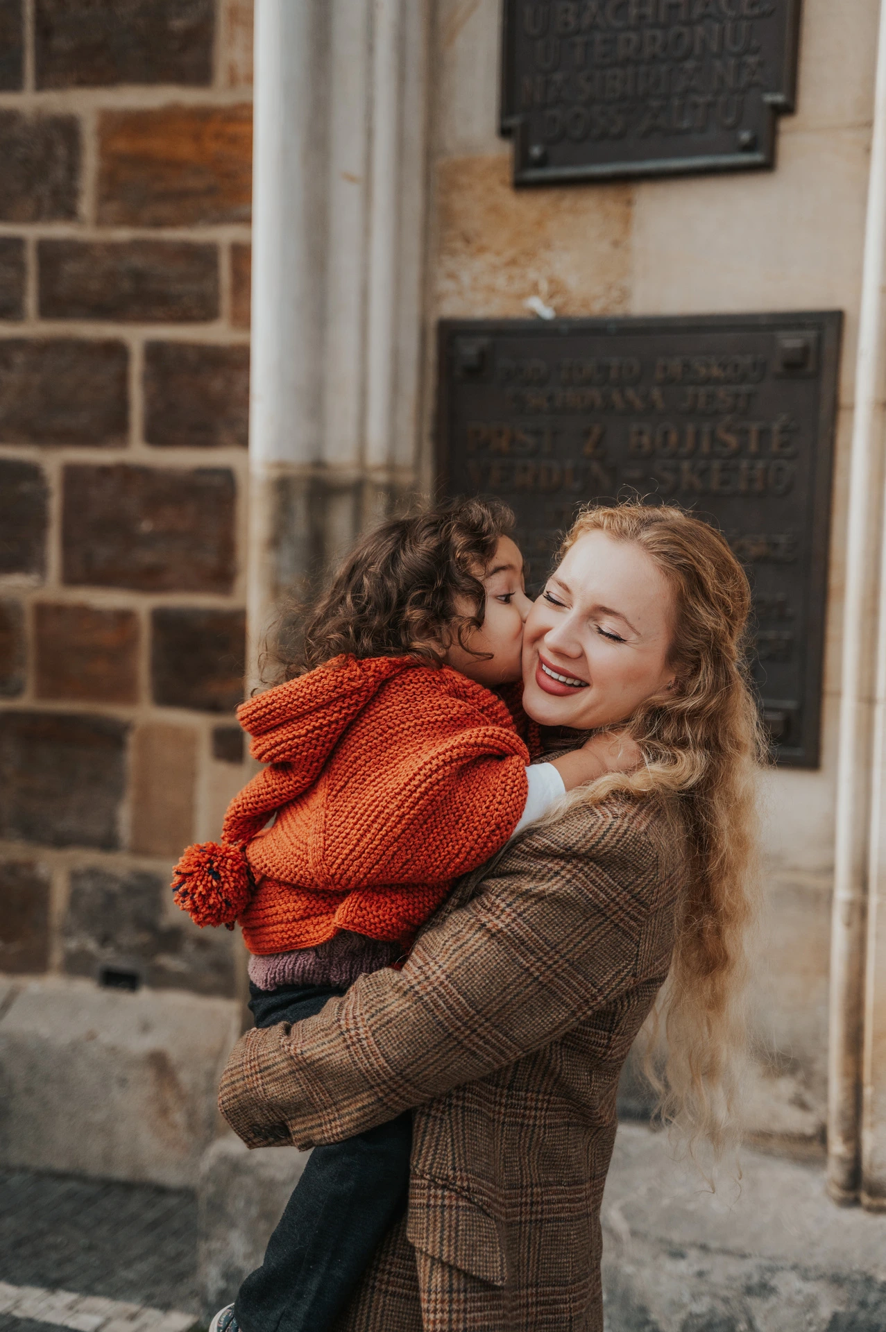 Mother laughing while holding her daughter in Old Town during a mother and daughter family photoshoot in Prague.