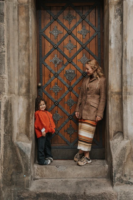 Prague family photoshoot: mother looking down at her daughter beside the Old Town doorway. Mother looking down at her daughter beside the Old Town doorway during a mother and daughter family photoshoot in Prague.