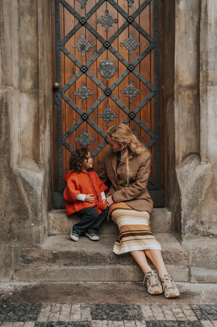 Prague family photoshoot: mother sitting beside her daughter in the Old Town doorway. Mother sitting beside her daughter in the Old Town doorway during a mother and daughter family photoshoot in Prague.
