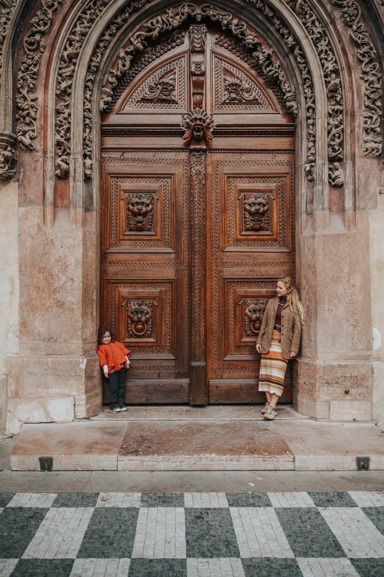 Wide portrait of mother and daughter at an ornate Old Town entrance during a mother and daughter family photoshoot in Prague.