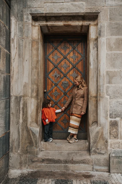 Prague family photoshoot: wide portrait of mother and daughter in the stone door frame. Wide portrait of mother and daughter in the stone door frame during a mother and daughter family photoshoot in Prague.