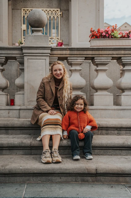 Prague family photoshoot: wide portrait of mother and daughter on the Old Town steps. Wide portrait of mother and daughter on the Old Town steps during a mother and daughter family photoshoot in Prague.