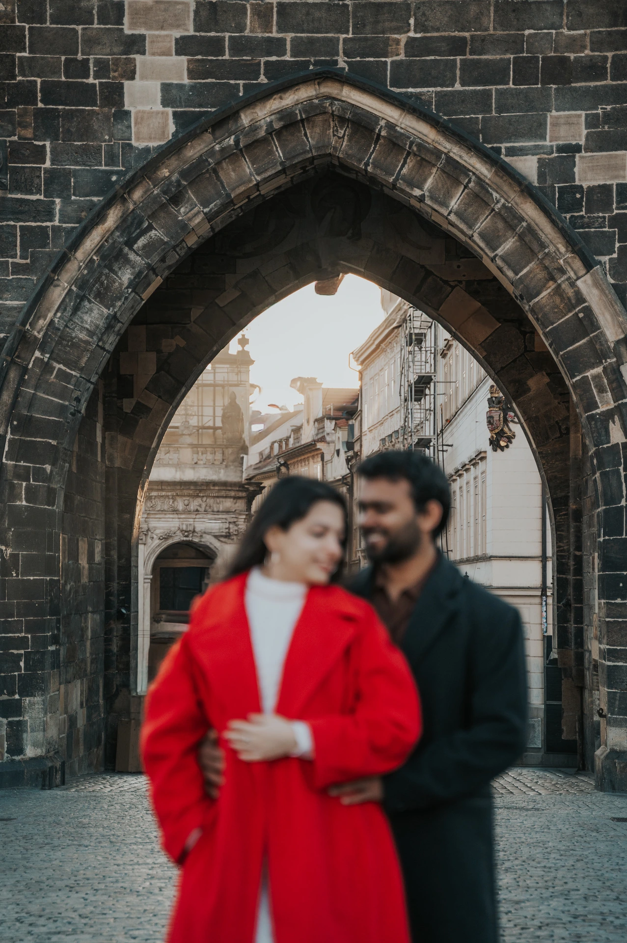 Close portrait of the couple smiling beneath the bridge arch during a couple photoshoot in Prague.