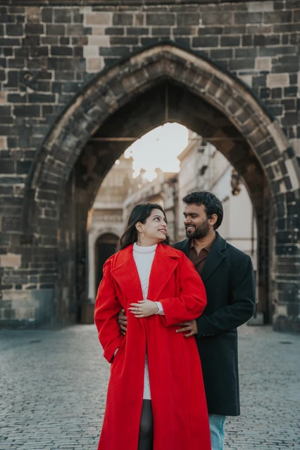 Prague couple photoshoot: couple embracing beneath a Gothic bridge arch. Couple embracing beneath a Gothic bridge arch during a couple photoshoot in Prague.