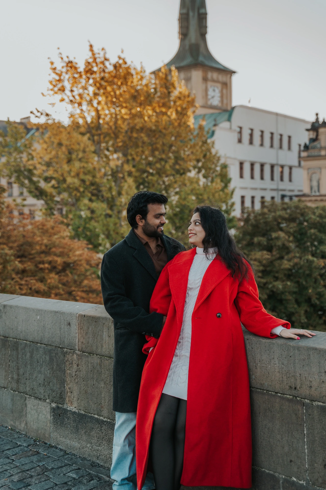 Couple looking at each other by the bridge wall during a couple photoshoot in Prague.