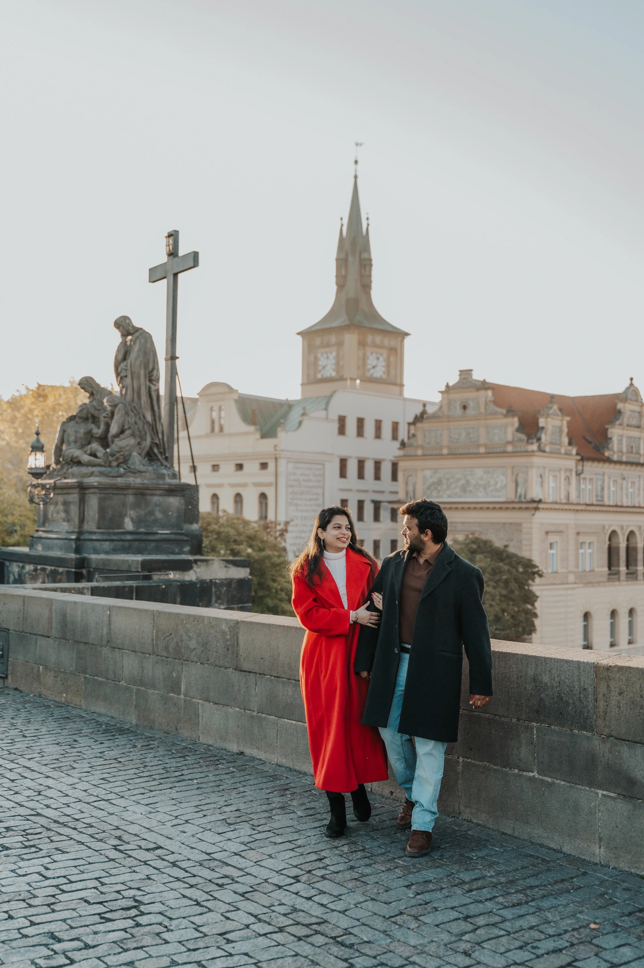 Couple pausing beside the statues on Charles Bridge during a couple photoshoot in Prague.