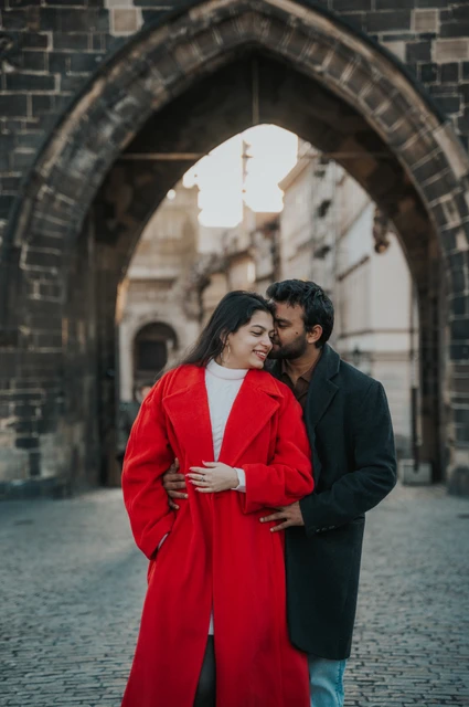 Prague couple photoshoot: couple sharing a kiss under the stone archway. Couple sharing a kiss under the stone archway during a couple photoshoot in Prague.
