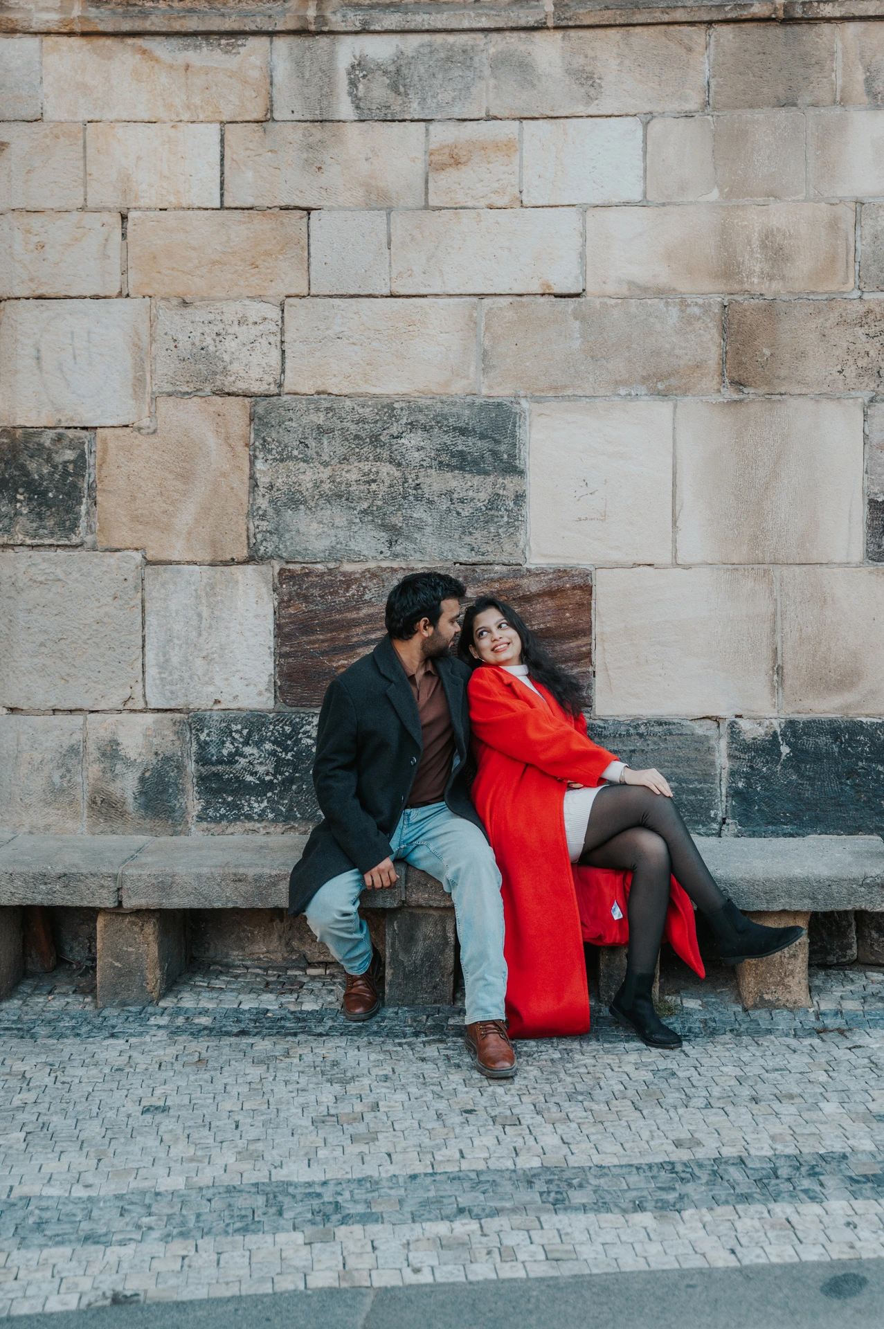 Couple sitting close on a stone bench during a couple photoshoot in Prague.