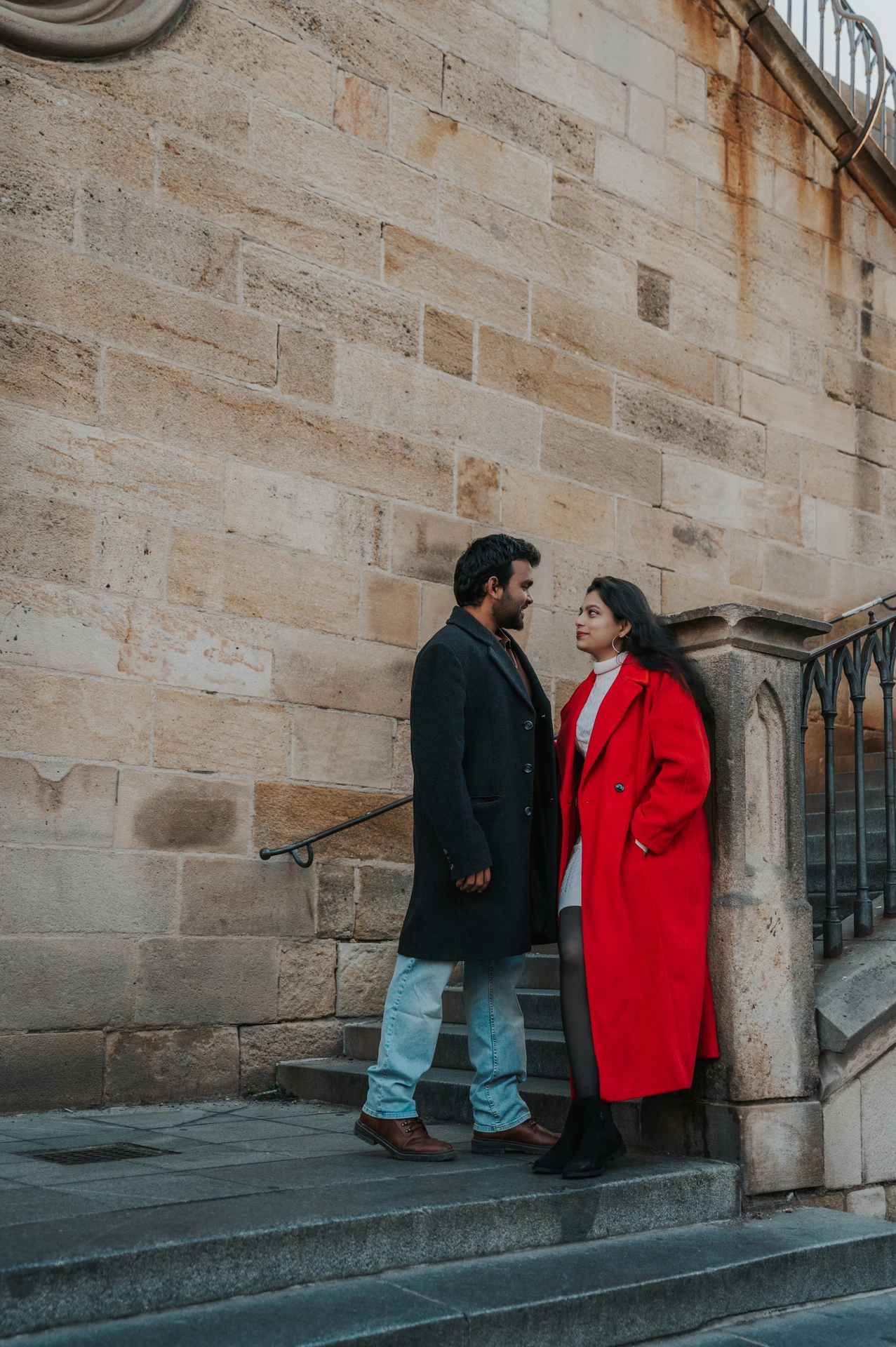 Couple smiling together against the pale stone wall during a couple photoshoot in Prague.