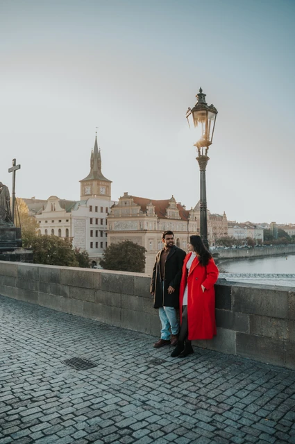Prague couple photoshoot: couple standing beneath a lamp beside the Vltava. Couple standing beneath a lamp beside the Vltava during a couple photoshoot in Prague.