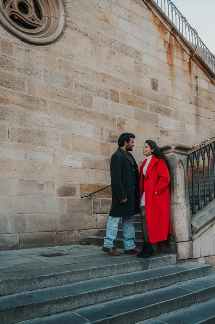 Prague couple photoshoot: couple standing on stone steps beside Charles Bridge. Couple standing on stone steps beside Charles Bridge during a couple photoshoot in Prague.