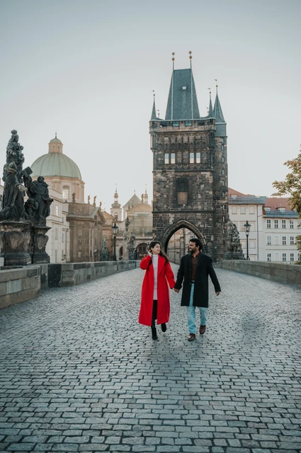 Couple walking towards the Old Town tower on Charles Bridge during a couple photoshoot in Prague.