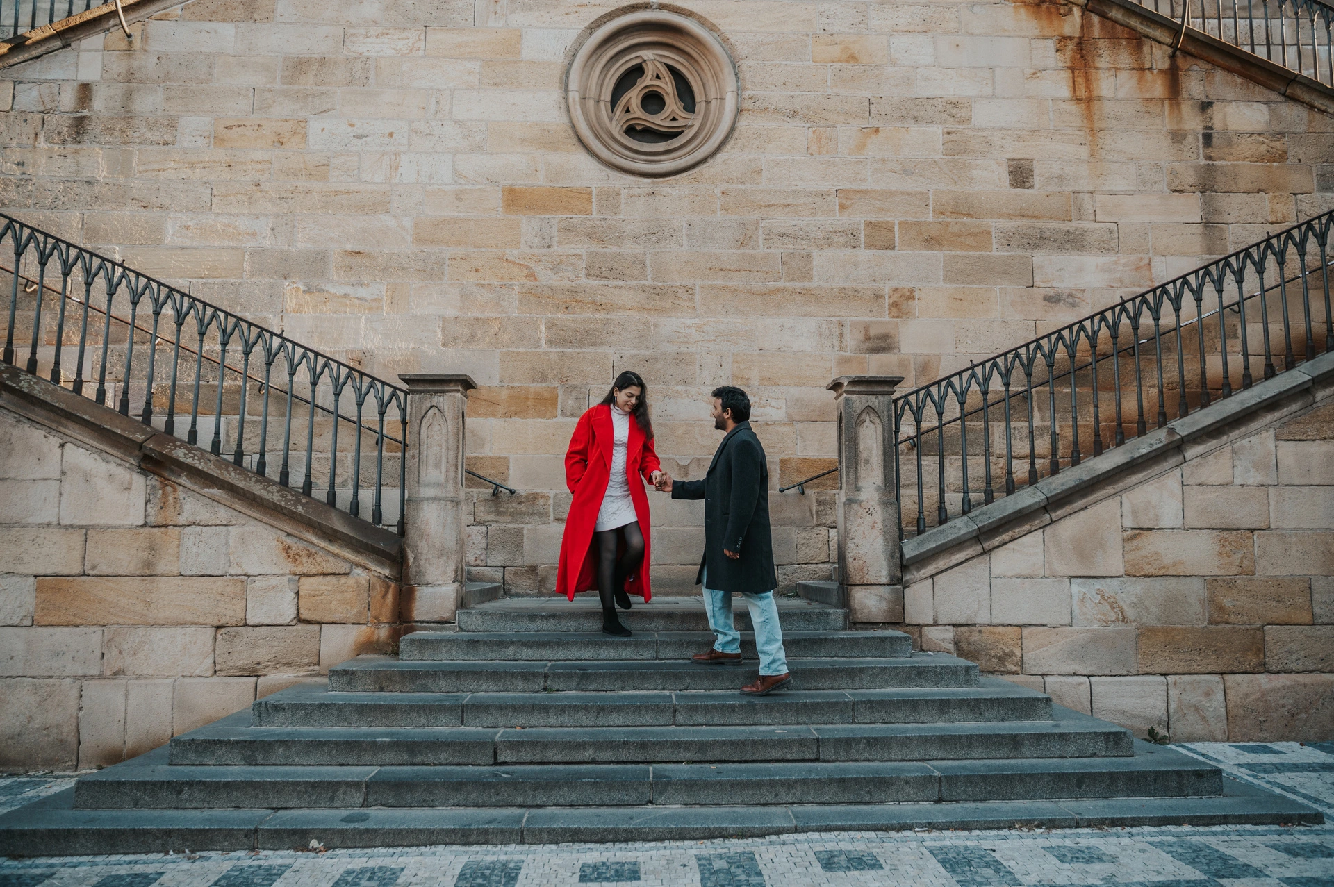 Wide portrait of the couple on the bridge-side staircase during a couple photoshoot in Prague.