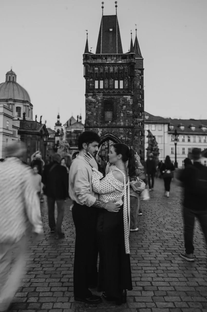 Prague couple photoshoot: black and white kiss near the Charles Bridge tower. Black and white kiss near the Charles Bridge tower during a couple photoshoot in Prague.