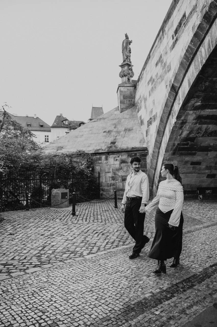 Prague couple photoshoot: black and white portrait beneath the Charles Bridge arch. Black and white portrait beneath the Charles Bridge arch during a couple photoshoot in Prague.