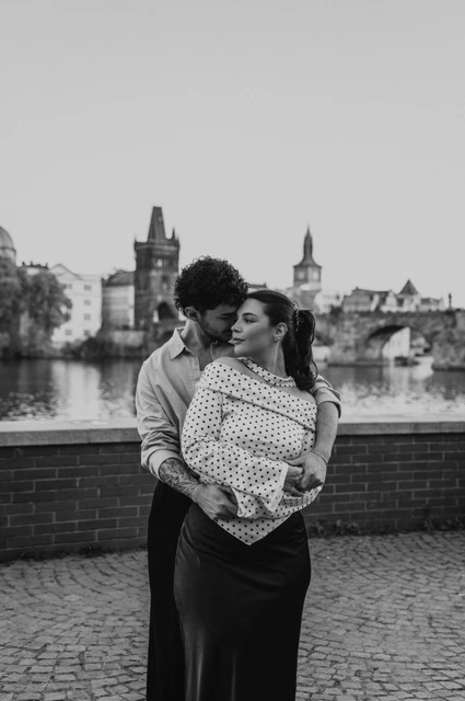 Prague couple photoshoot: black and white portrait of a close embrace by the Vltava. Black and white portrait of a close embrace by the Vltava during a couple photoshoot in Prague.