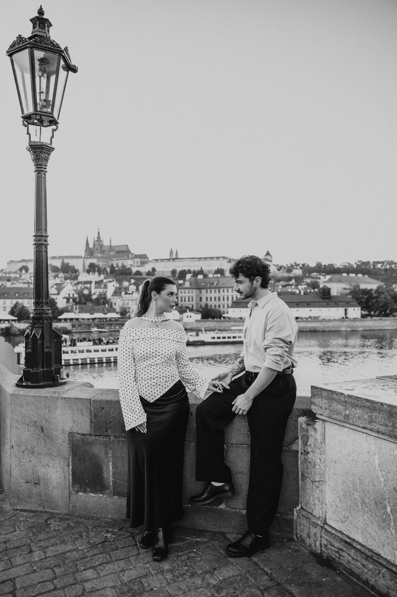 Black and white portrait of the couple beside the bridge lamp during a couple photoshoot in Prague.