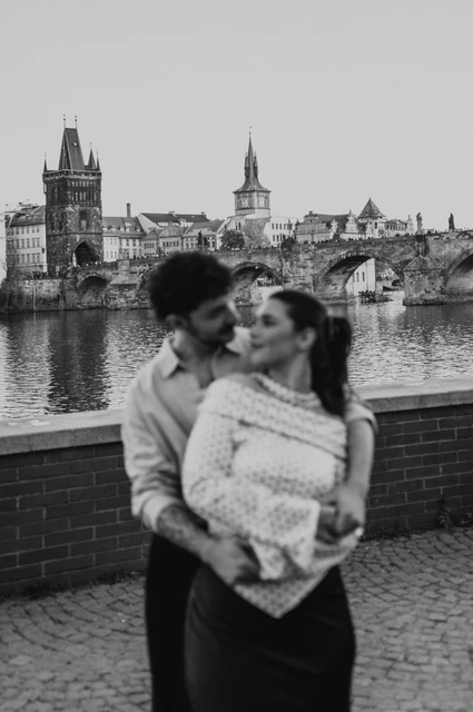 Prague couple photoshoot: black and white portrait of the couple laughing beside the river. Black and white portrait of the couple laughing beside the river during a couple photoshoot in Prague.