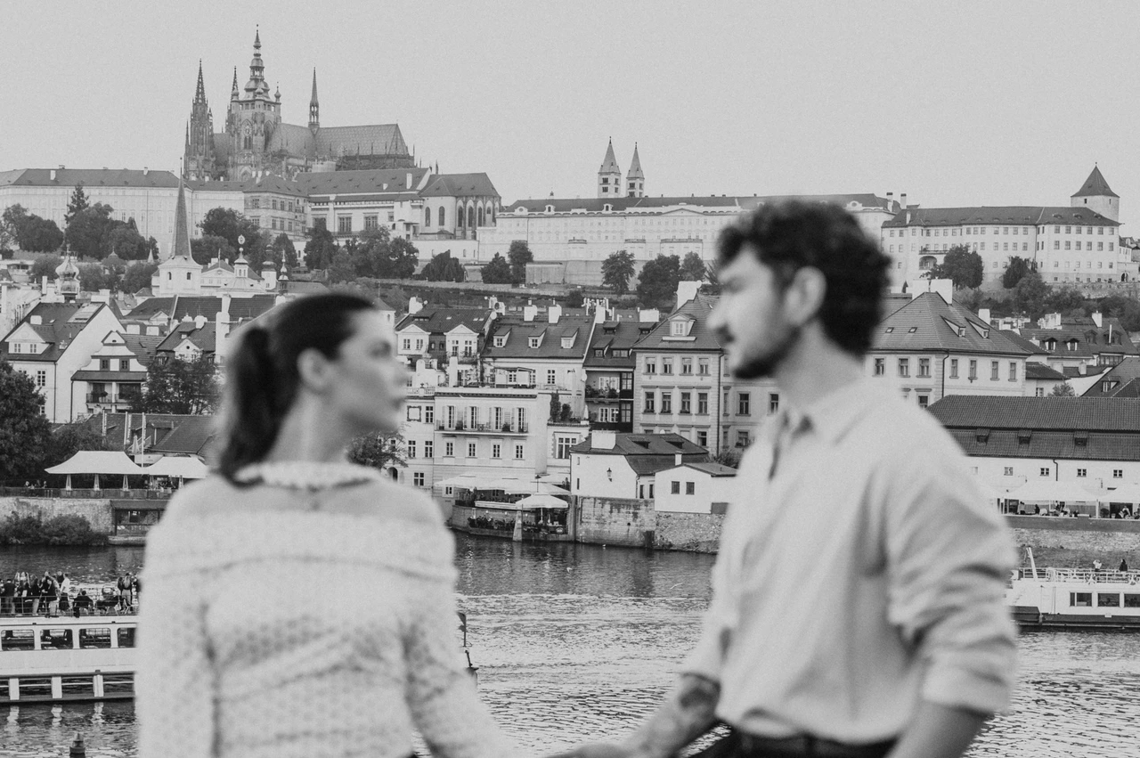 Prague couple photoshoot: black and white portrait with Prague Castle in the distance. Black and white portrait with Prague Castle in the distance during a couple photoshoot in Prague.