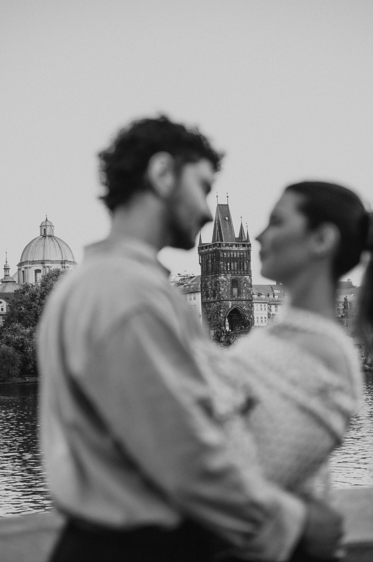 Black and white soft-focus portrait by the river during a couple photoshoot in Prague.