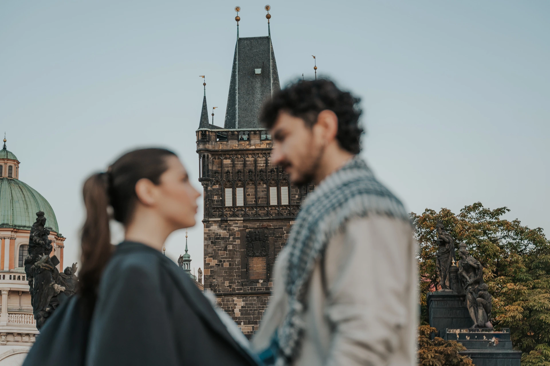 Close portrait of the couple in front of the bridge tower during a couple photoshoot in Prague.
