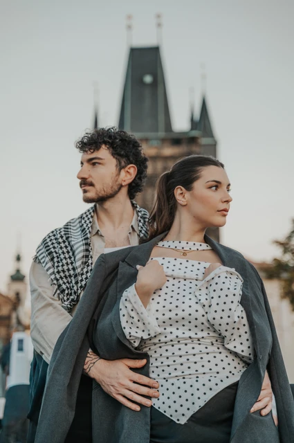 Couple embracing beneath a checked wrap beside the tower during a couple photoshoot in Prague.