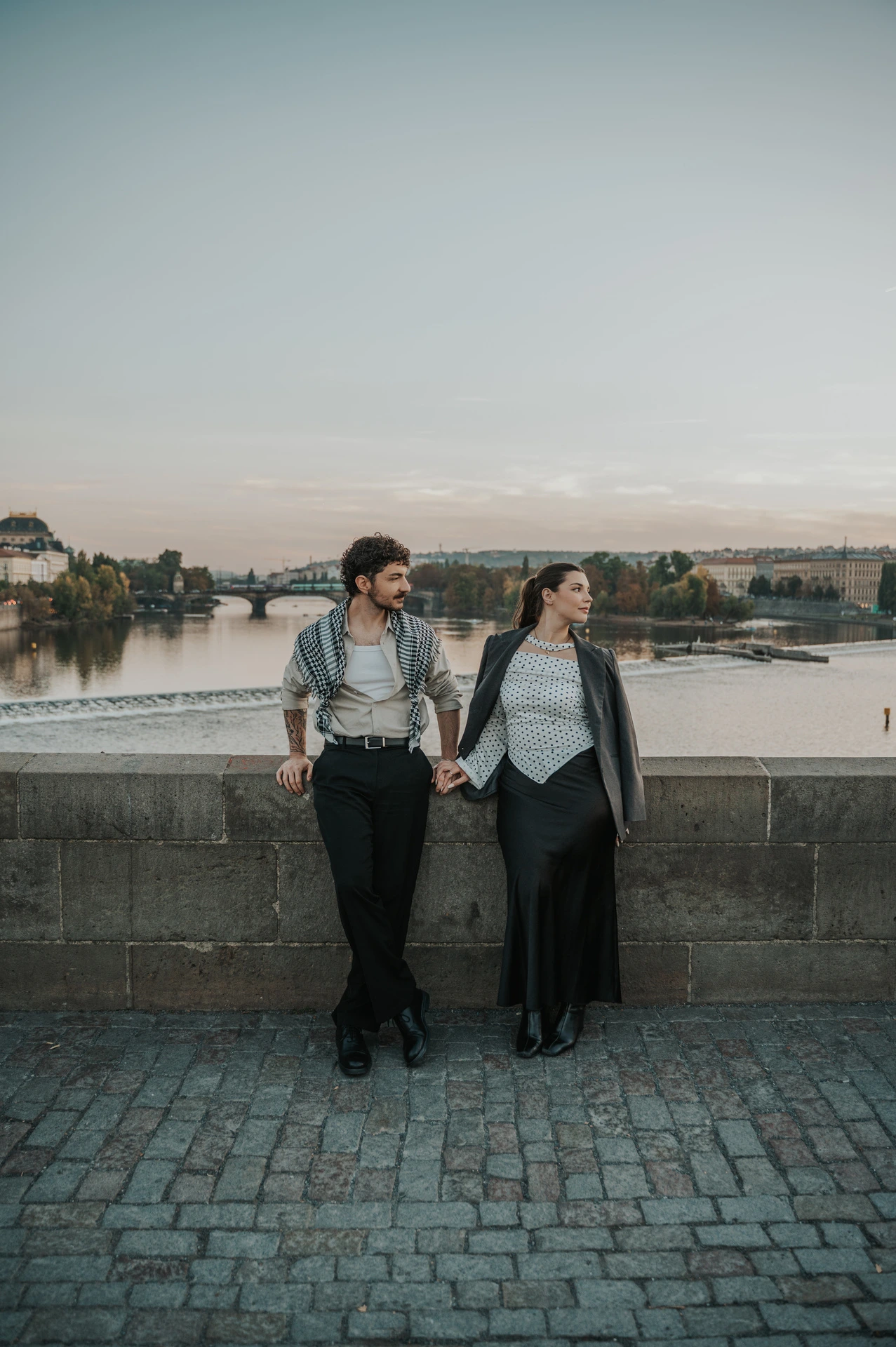 Couple holding hands at the bridge parapet during a couple photoshoot in Prague.